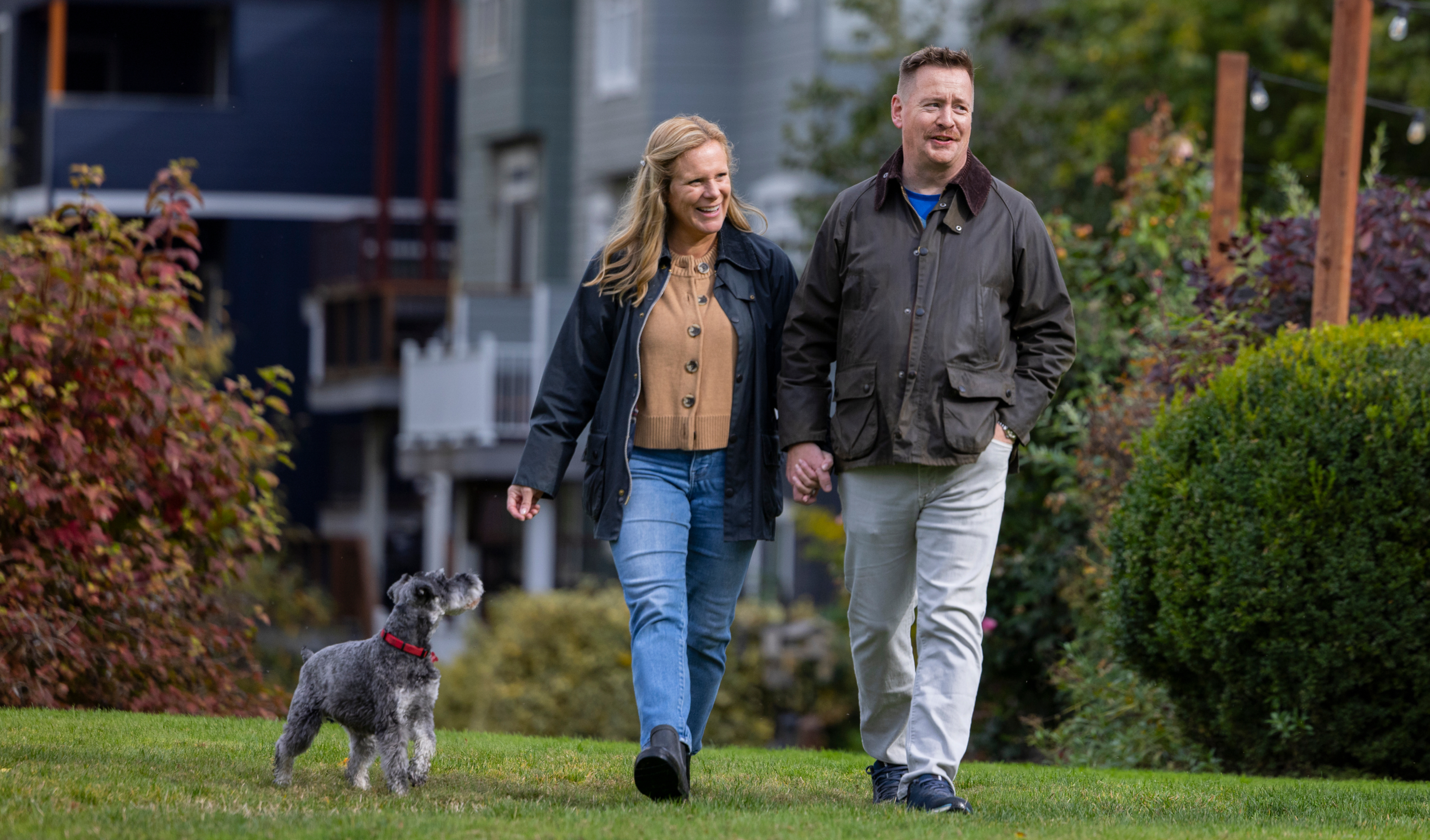 man and woman holding hands walking a dog