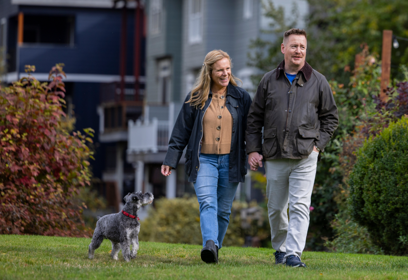 man and woman holding hands walking a dog