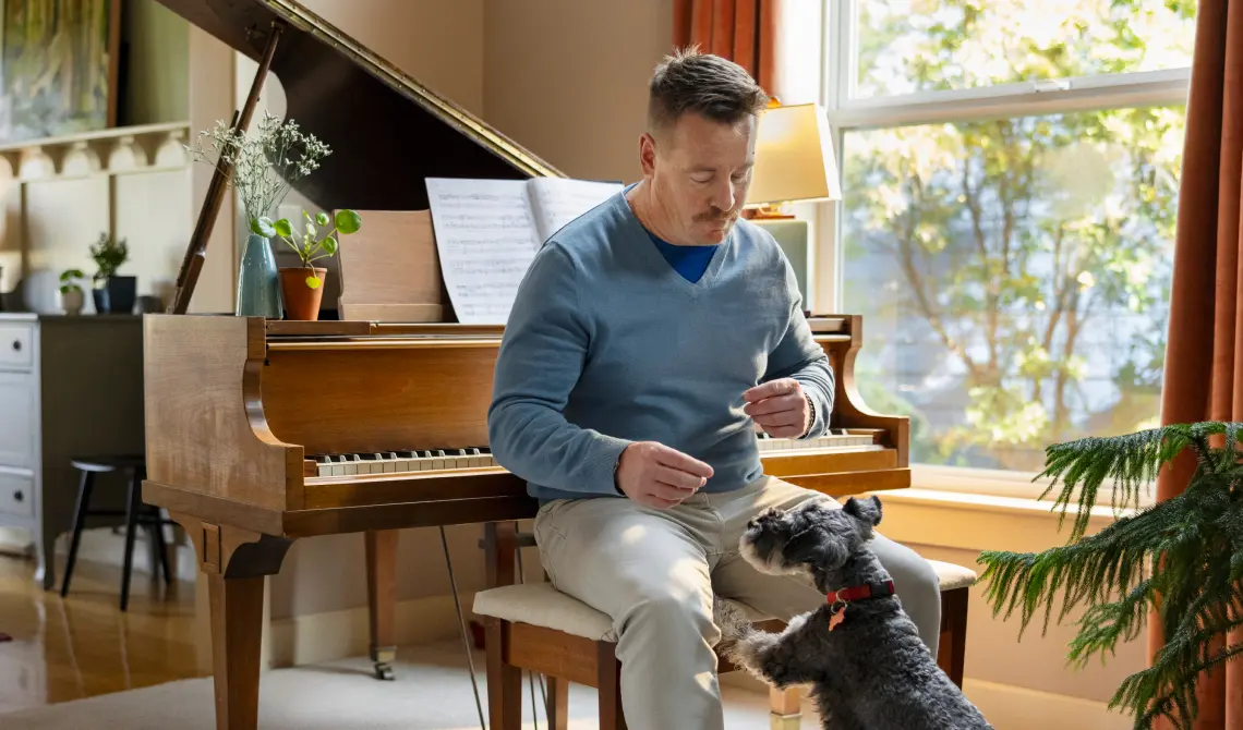 Man sitting at piano, playing with dog