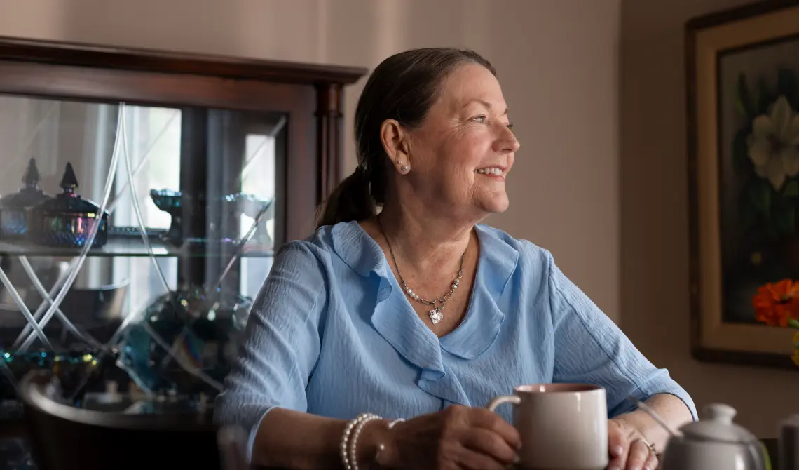 woman sitting at a table, enjoying a cup of coffee