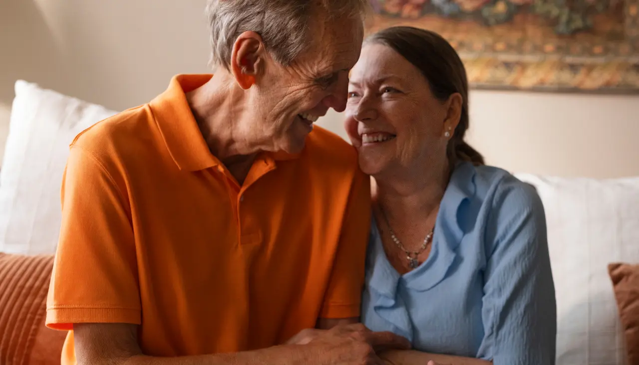 senior couple sitting together in their home smiling at each other