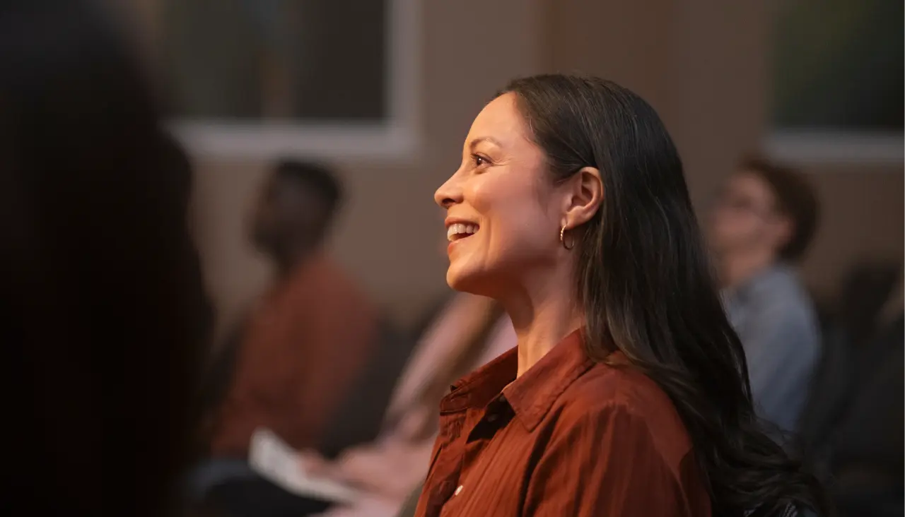 woman smiling brightly as she sits in an engaged crowd of people