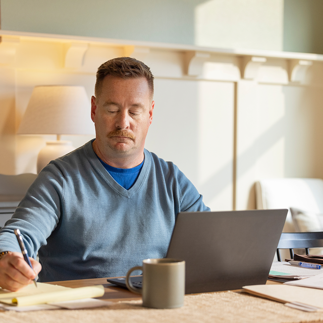 Andrew, a real ISM patient, works on his laptop at a table